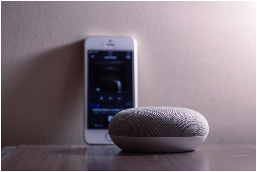 A modern smart speaker and smartphone on a wooden