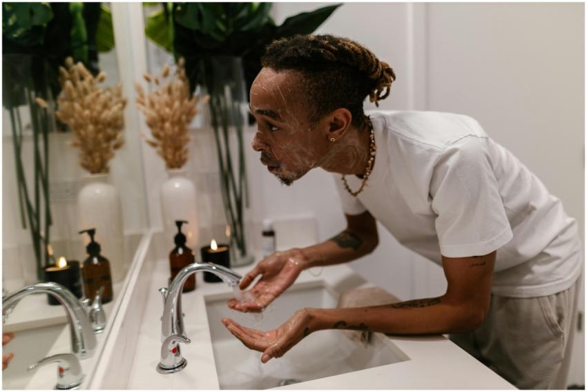 Man washing face in bathroom sink, showcasing a mo