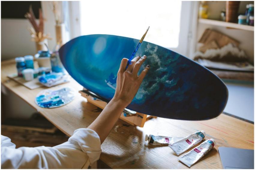Close-up of an artist painting a surf-themed surfb