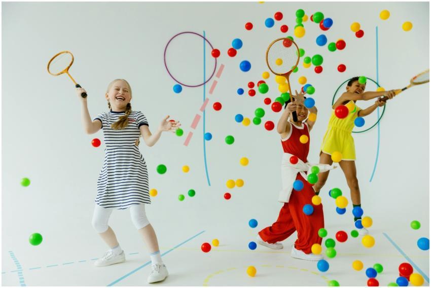 Children playing indoors with rackets and colorful