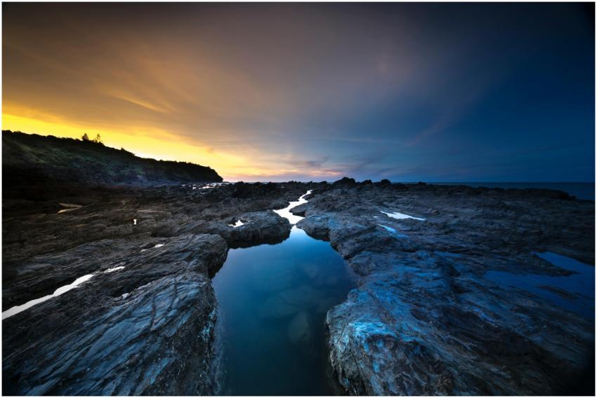 Sunset over rugged rocks and ocean, capturing vibr