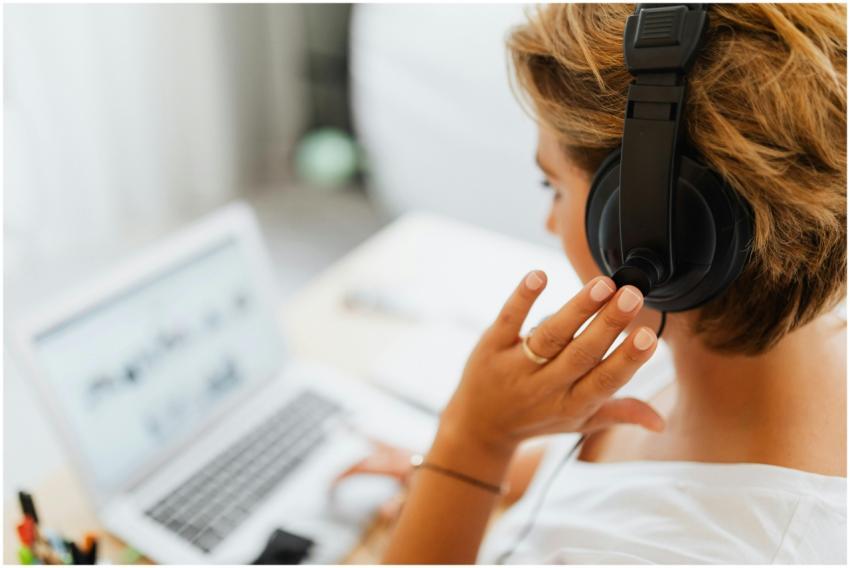 Woman at home using headphones and laptop for onli
