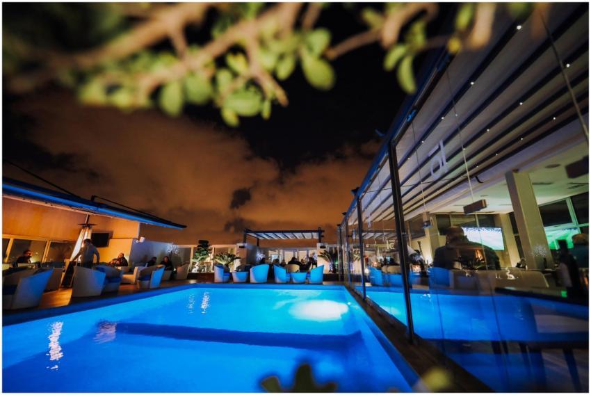 A vivid nighttime scene of a modern hotel poolside