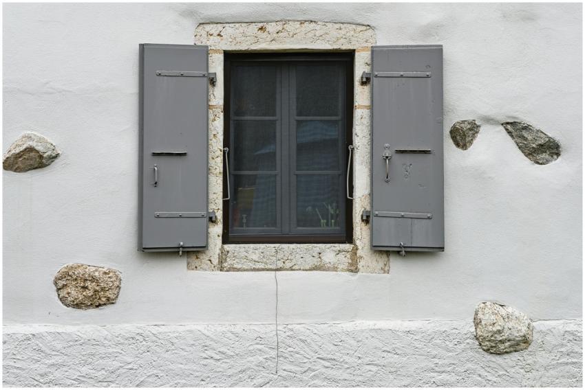 Close-up of a rustic window with gray shutters, st