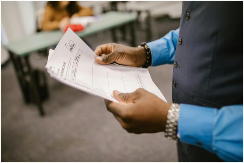 An instructor examining test papers in a classroom
