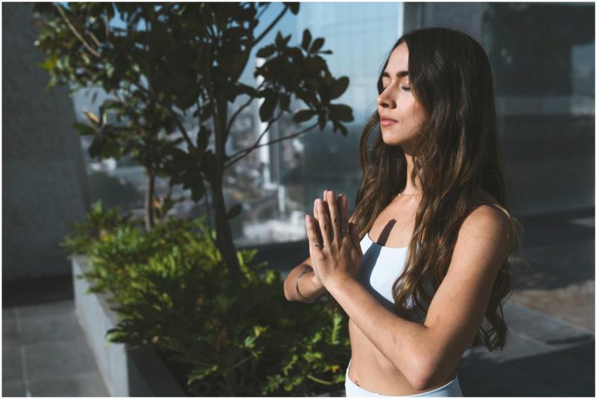 A woman practicing meditation outdoors under sunli