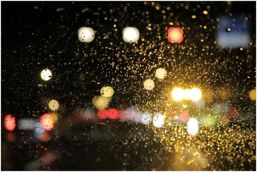 Street lights glistening through raindrops on a ca