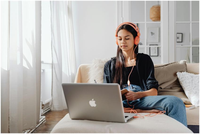 Teenage girl wearing headphones using a laptop for