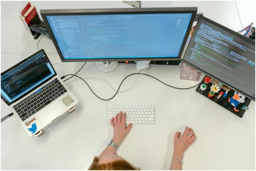 A female software engineer coding on dual monitors