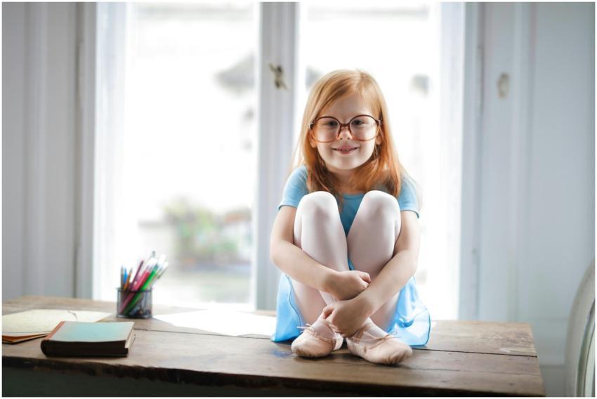 Joyful red haired schoolgirl in blue dress and bal