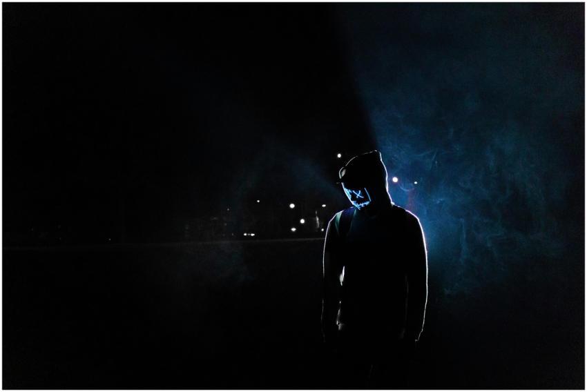 Silhouette of a man in a glowing LED mask and hood