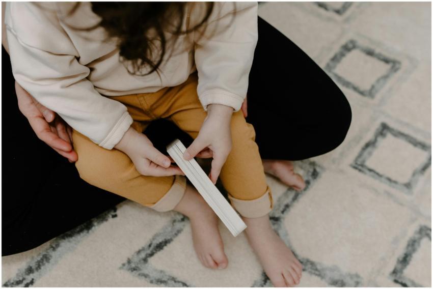 A child with a book sitting on a parent's lap in a