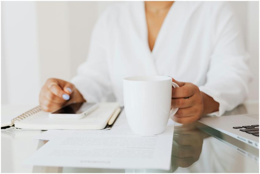Woman holding a white mug at a desk with documents