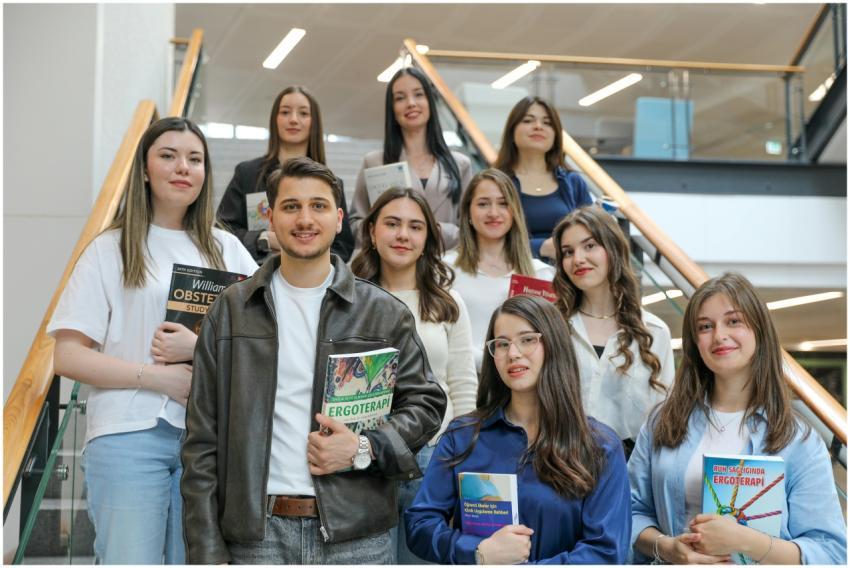 Diverse group of students smiling on stairs, holdi