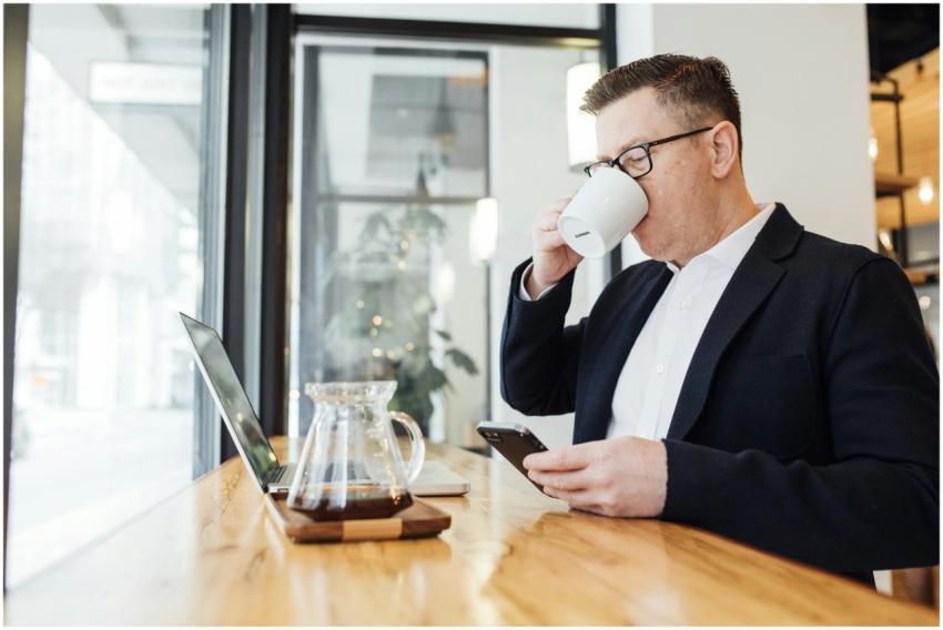 Professional man drinking coffee while using phone