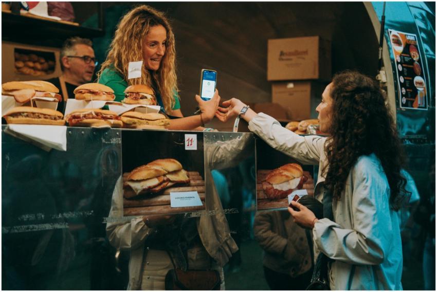 Two women exchanging digital payment at a food tru