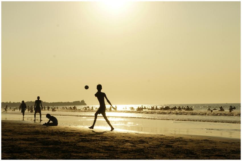 Silhouette of children playing on a crowded beach