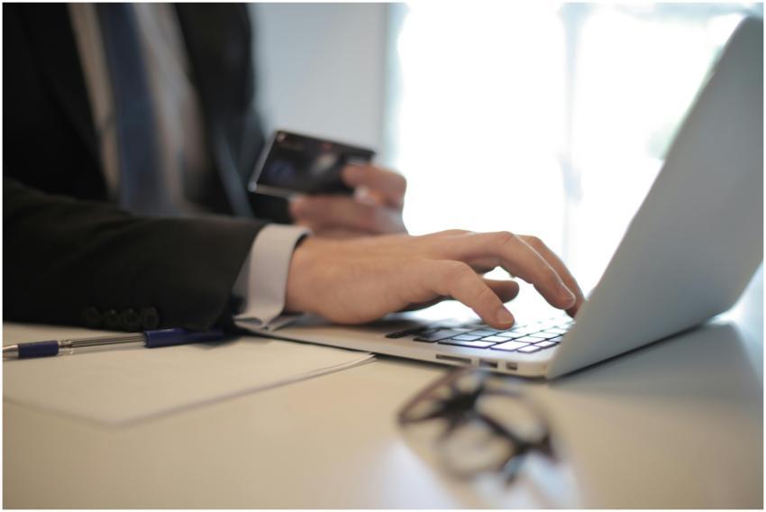 Man in suit using laptop and credit card for onlin