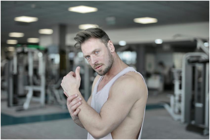 Confident muscular man poses in a modern gym, show