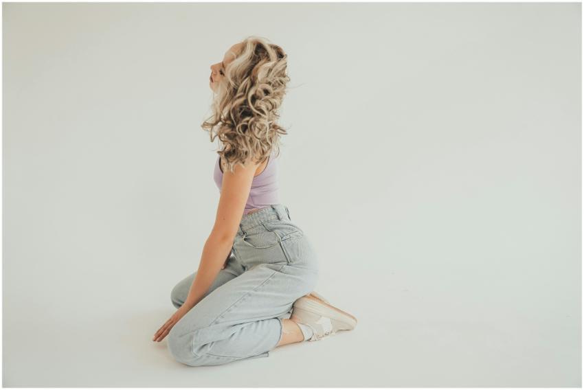 A fashionable woman with curly hair poses in denim