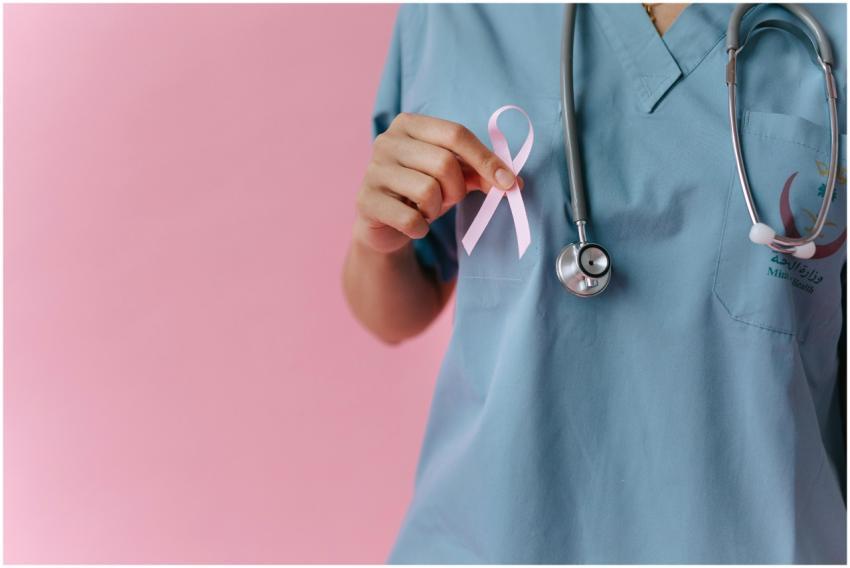 Healthcare worker in scrubs holds a pink breast ca