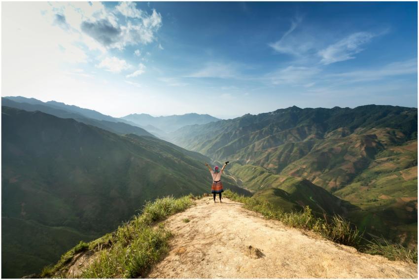 A lone hiker raises arms in victory on a scenic mo