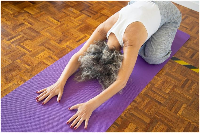 Elderly woman performing yoga pose on a purple mat