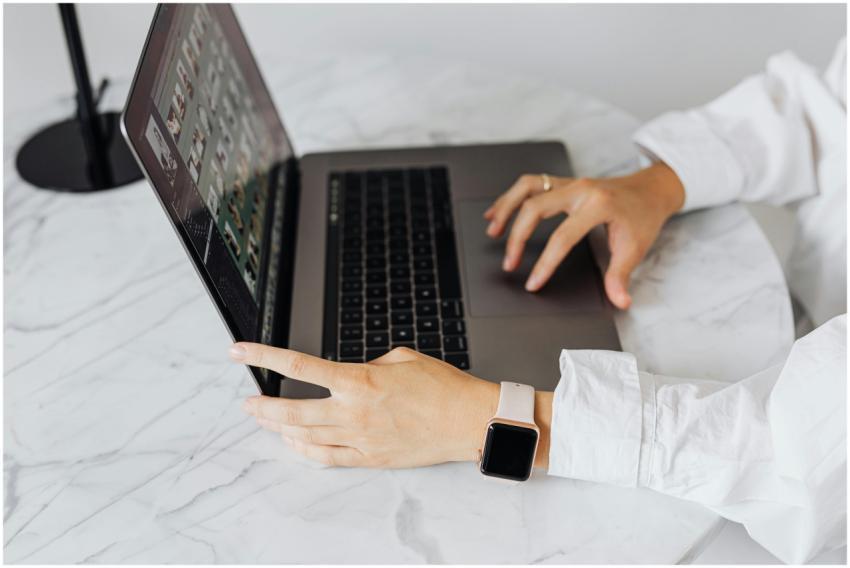 Person typing on a laptop at a marble table, weari