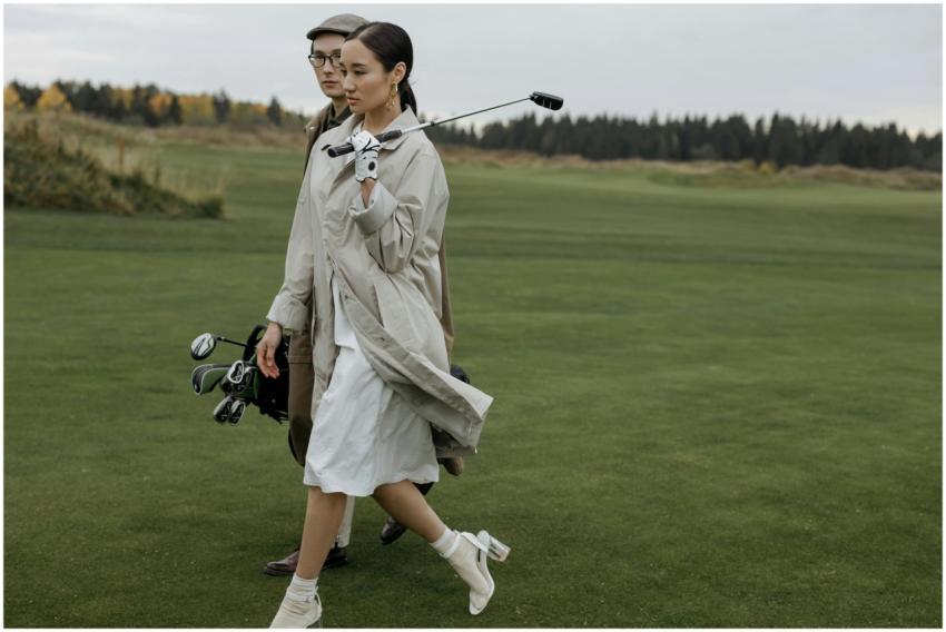 A fashionable couple walking with golf equipment o