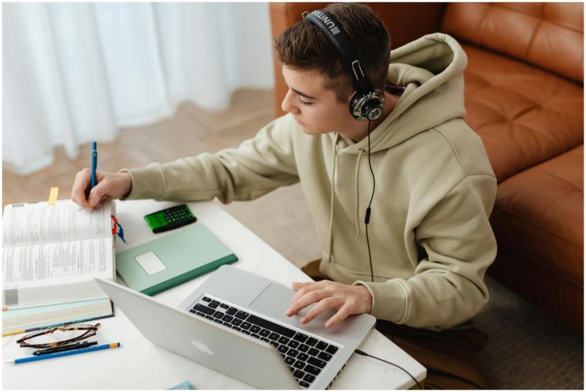 Teen studying at home using laptop and books, wear
