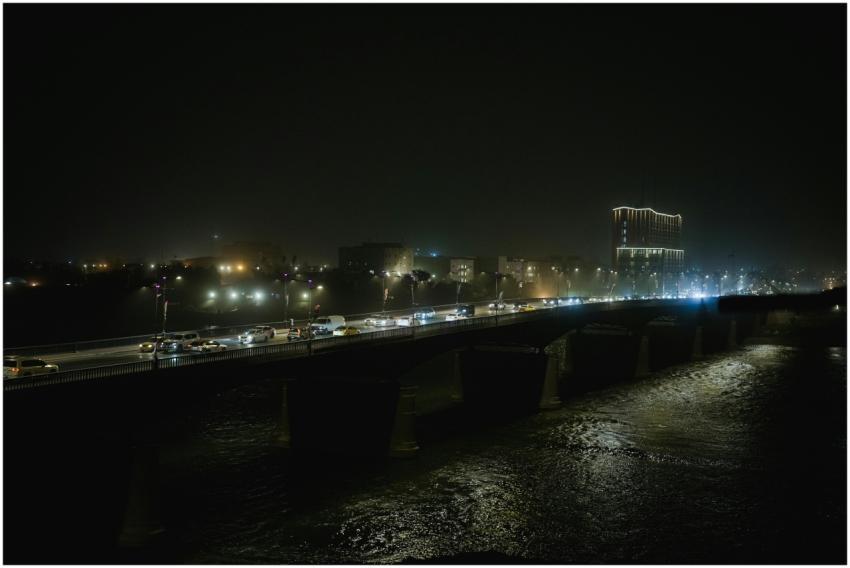 A night scene featuring a bridge with bustling tra