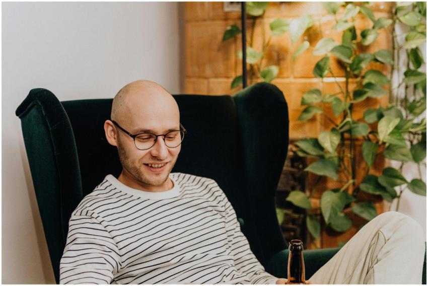 A young man relaxes at home, enjoying a drink and