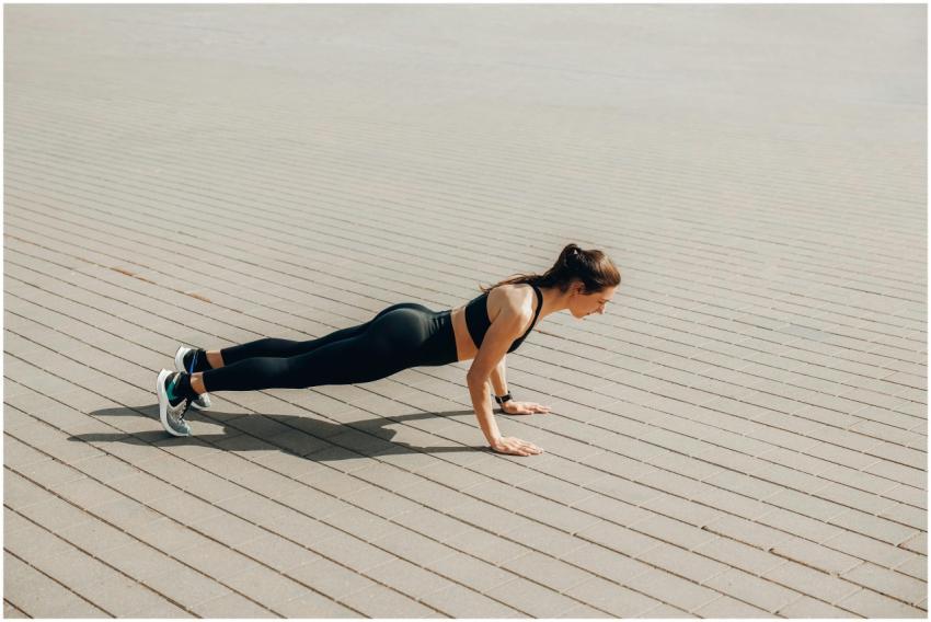 A woman in activewear performs a plank exercise ou