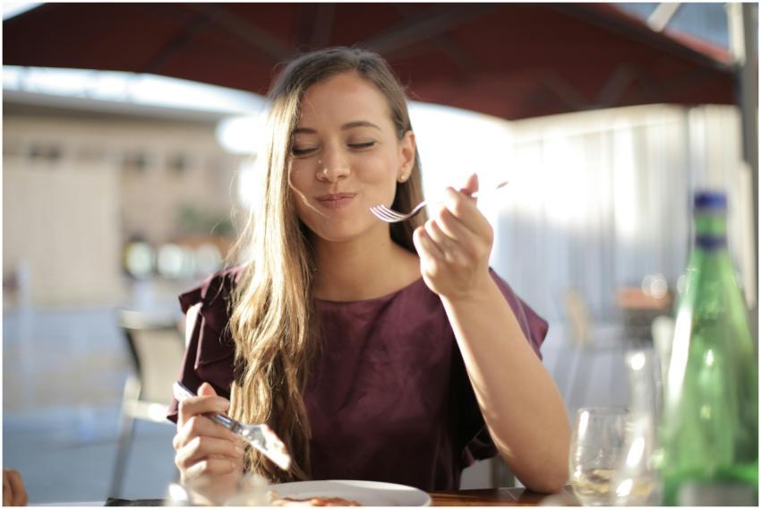 A woman savoring her meal with a smile, dining out