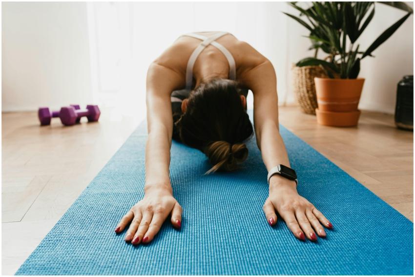 Woman doing a child's pose on a blue yoga mat at h