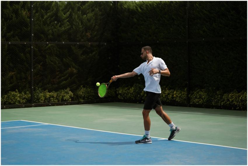 Adult male playing tennis outdoors, showcasing a f