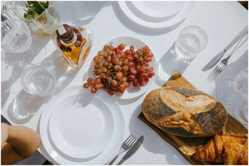 A stylish dining table setting featuring bread, gr