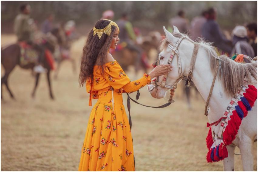 A woman in a vibrant dress stands tenderly touchin