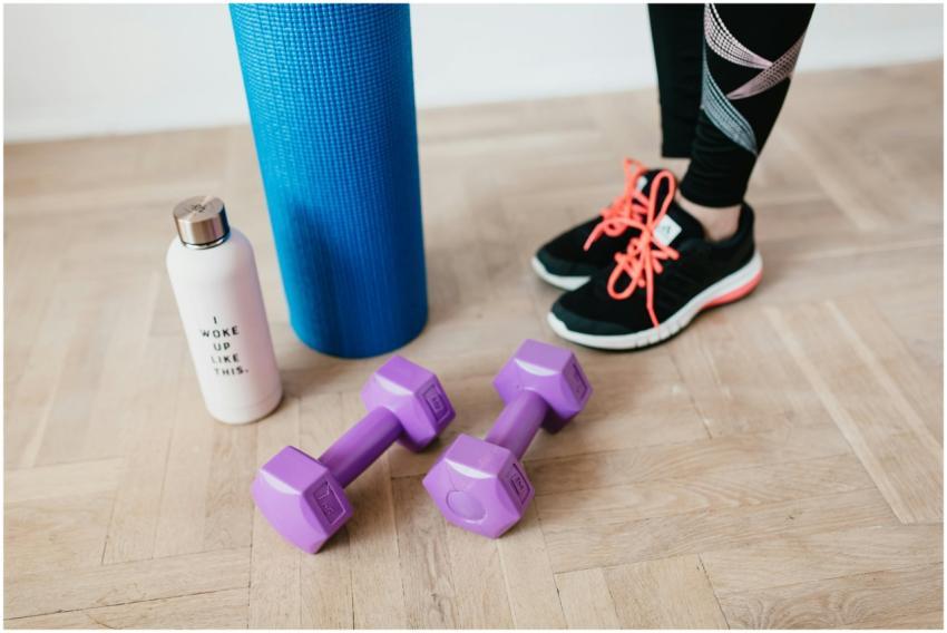 A pair of sneakers, purple dumbbells, yoga mat and