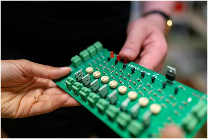 Close-up of hands holding a green circuit board us