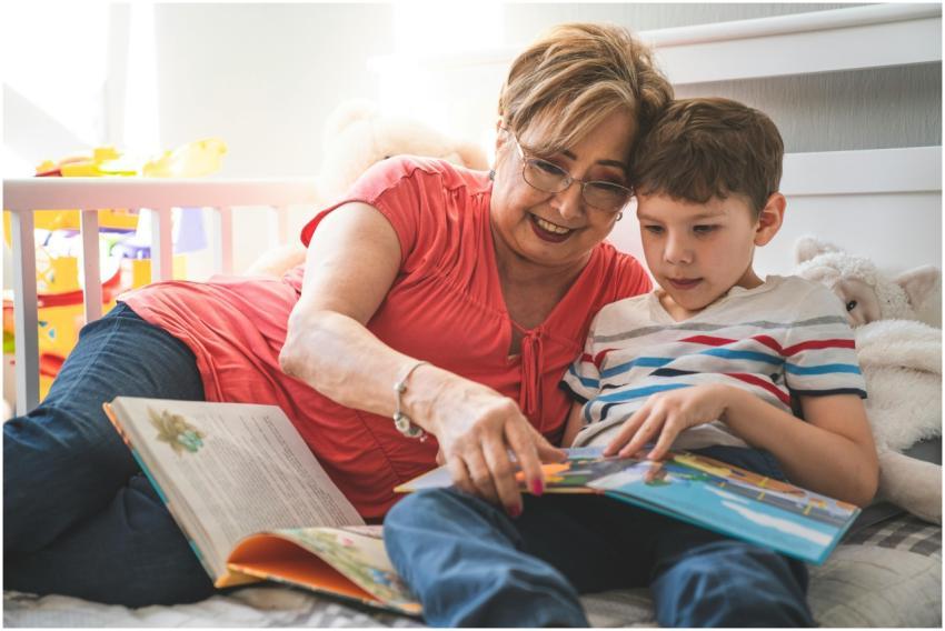 Elderly woman reading a book with her grandson on