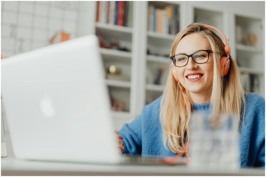 Young woman with glasses and headphones smiling wh