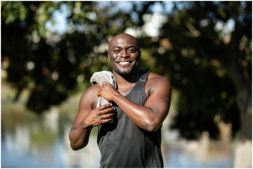 Happy man in a gray tank top outdoors, holding a t