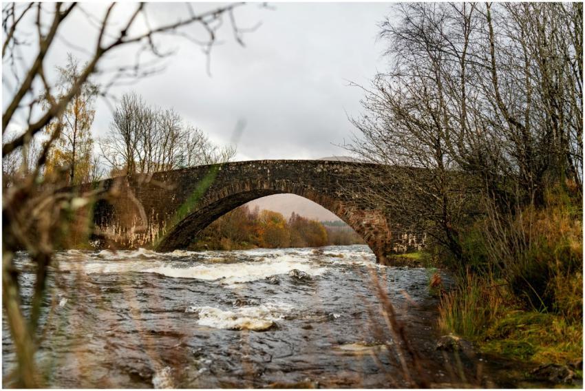 A picturesque stone bridge spans a flowing river a