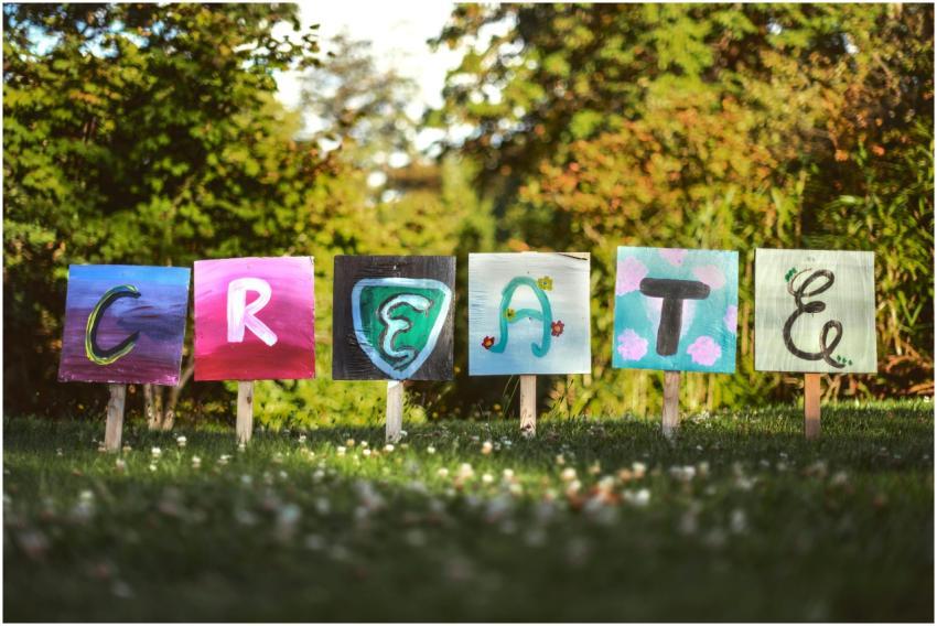 Vibrant painted signs spelling 'CREATE' in a lush