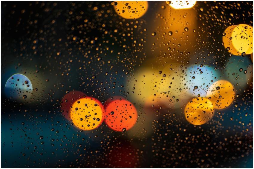 Raindrops on window with vibrant bokeh lights crea