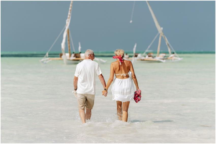 An elderly couple holds hands while walking on the