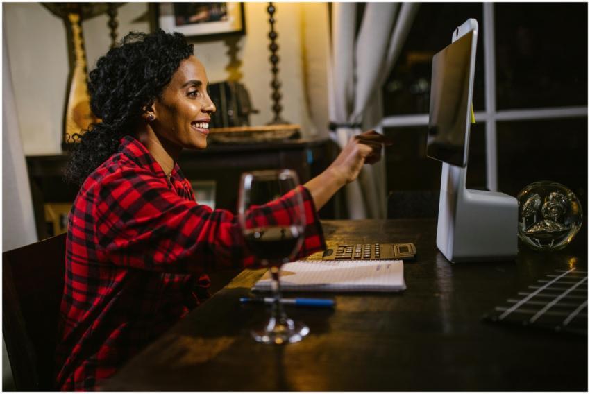 Woman in plaid shirt using a computer and smiling,