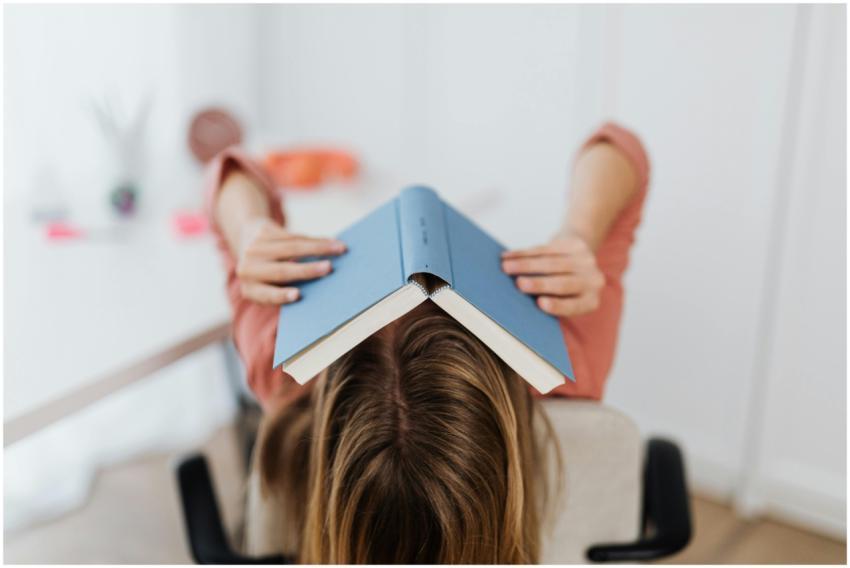 Adult woman covering face with a book in an indoor