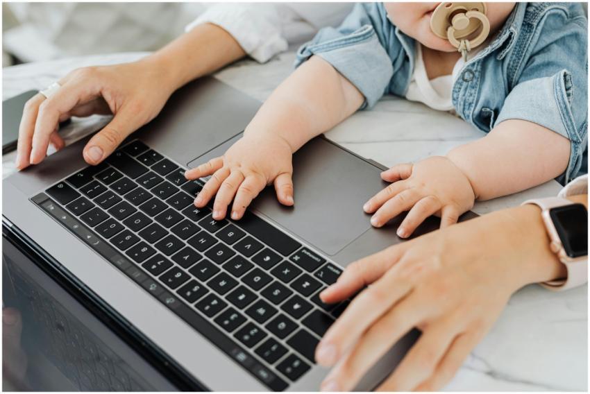 A parent and baby engaging with a laptop keyboard
